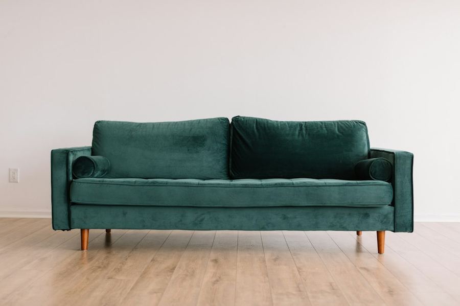 Green sofa on a wood floor — typical furniture ready for junk removal
