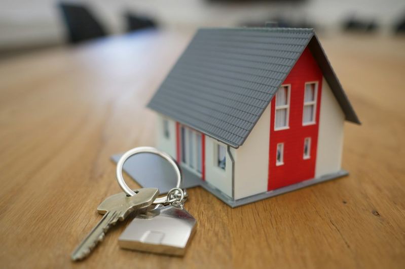 House keys and a small house model on a wooden table
